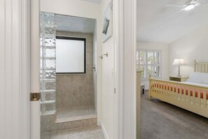 Ein Zimmer mit einem Bett, einem Nachttisch, einer Lampe und einem Fenster mit Jalousien.