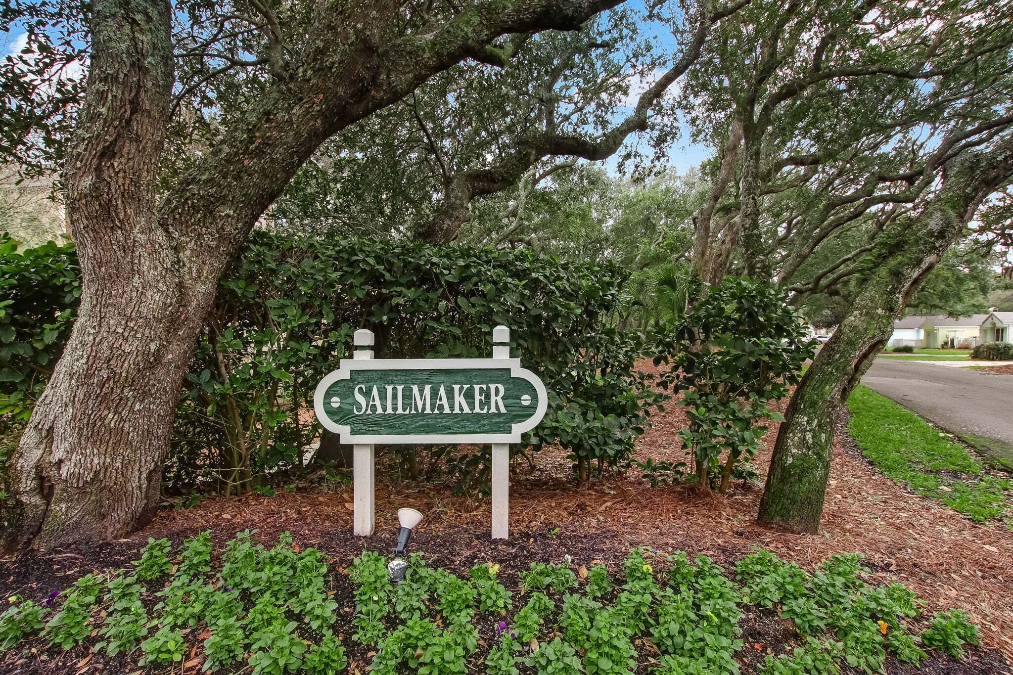 A sign with the name 'SAULMAKER' in a lush, green setting with trees and shrubs.