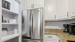 A stainless steel refrigerator with a freezer compartment, white cabinetry, and a granite countertop. - Sailmaker Gated Complex: Near Pool & Beach (Fernandina Beach)