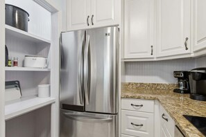 A stainless steel refrigerator with a freezer compartment, white cabinetry, and a granite countertop. - Sailmaker Gated Complex: Near Pool & Beach (Fernandina Beach)