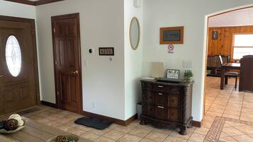 Une pièce avec une porte en bois, une pancarte indiquant « CLÉS », une pancarte « DÉFENSE DE FUMER », une pancarte « WI-FI » et un coin repas avec une table et des chaises.
