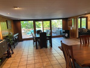 A spacious indoor area with a large dining table, multiple chairs, and a grill station.