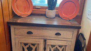 A wooden cabinet with two doors, a window above, and a potted plant on top.