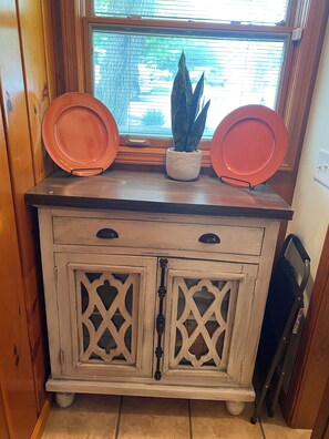 A wooden cabinet with two doors, a window above, and a potted plant on top.