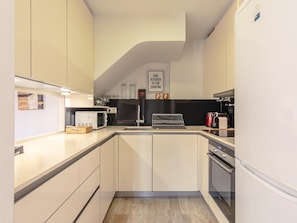 A modern kitchen with white cabinets, a microwave, a kettle, and a coffee maker. - Giralda Views Atico Duplex con terraza privada (Sevilla.)