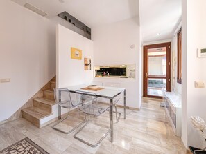 A modern kitchen with a built-in oven, a dining area with a glass table and chairs, and a staircase leading to another level. - Giralda Views Atico Duplex con terraza privada (Sevilla.)