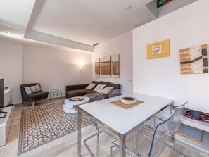 Una sala de estar moderna con un sofá blanco, una mesa de centro y un comedor con una mesa y sillas blancas.