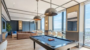 Ein moderner Lounge-Bereich mit Billardtisch, Sitzgelegenheiten und großen Fenstern mit Blick.
