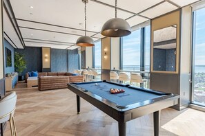 Ein moderner Lounge-Bereich mit Billardtisch, Sitzgelegenheiten und großen Fenstern mit Blick.
