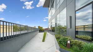 Ein modernes Gebäude mit Glasfassade, einem Betonweg und einem Metallzaun.