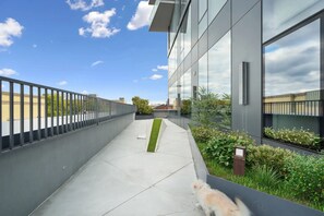 Ein modernes Gebäude mit Glasfassade, einem Betonweg und einem Metallzaun.