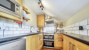A kitchen with wooden cabinets, a stainless steel oven, a microwave, and a dish rack. - Hayloft-Sleeps 3-with Enclosed terrace (Dereham)