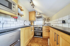 A kitchen with wooden cabinets, a stainless steel oven, a microwave, and a dish rack. - Hayloft-Sleeps 3-with Enclosed terrace (Dereham)