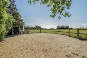 A gravel path leading to a building with a wooden fence and trees. - Hayloft-Sleeps 3-with Enclosed terrace (Dereham)