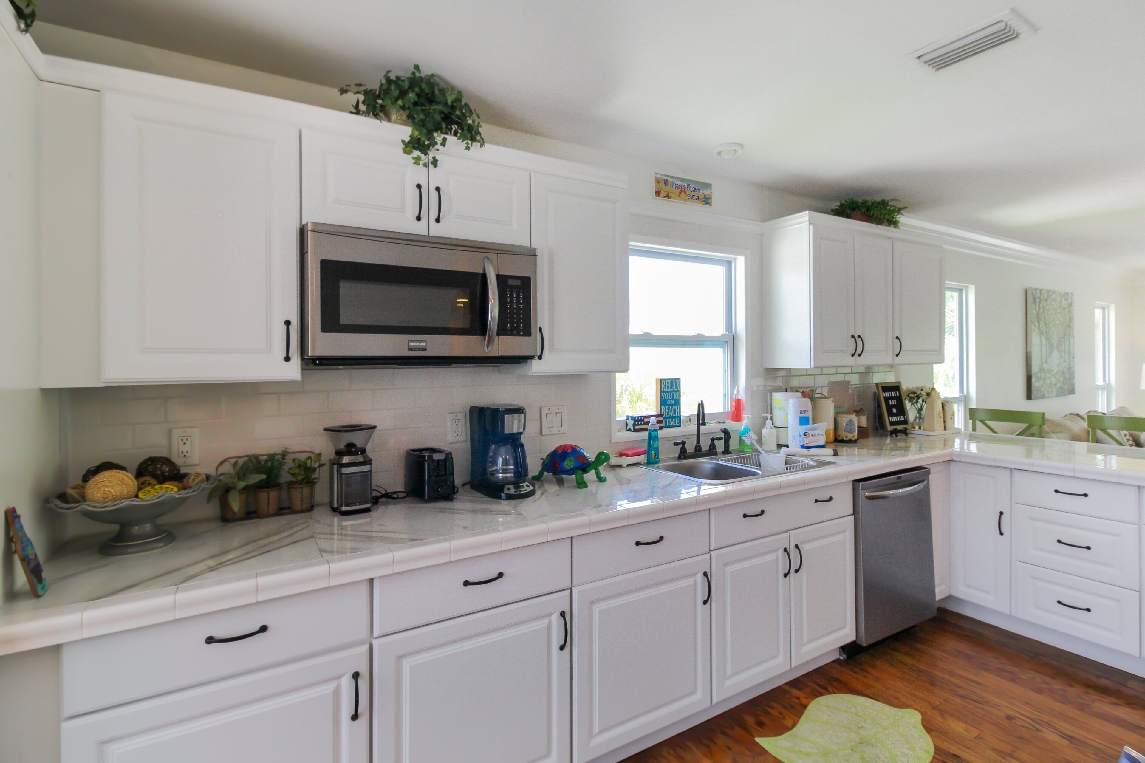 A modern kitchen with white cabinetry, a stainless steel microwave, and a coffee maker.