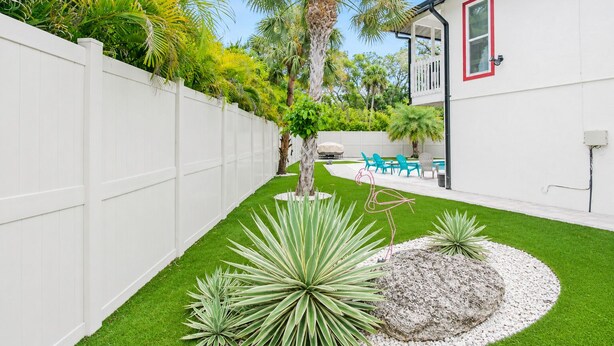 A backyard with artificial grass, a white fence, a palm tree, and outdoor furniture. - Private Siesta Key Pool Home Near Beaches - Siesta Sol (Sarasota)