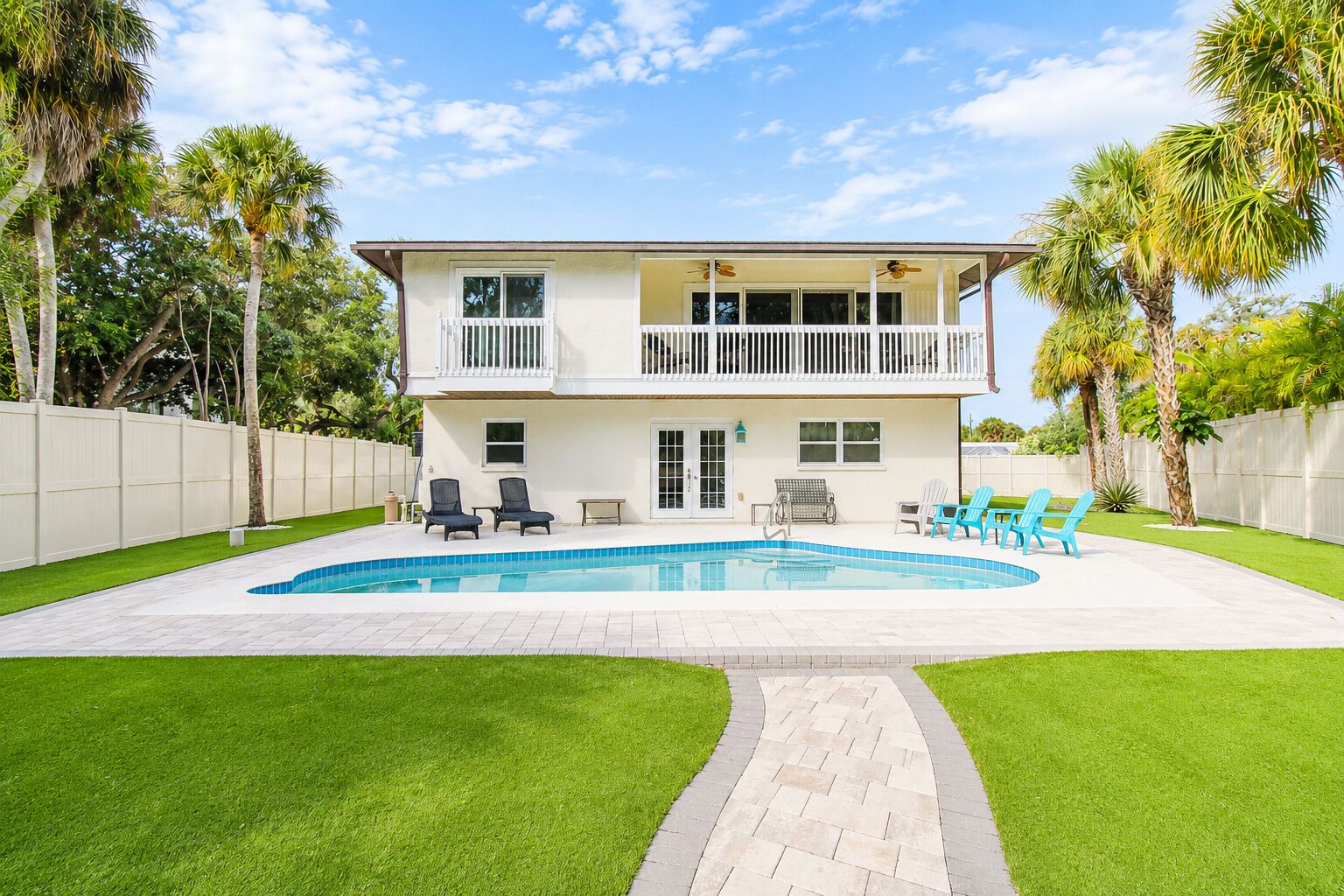 A two-story house with a swimming pool, a covered patio, and a fenced yard.