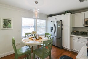 A kitchen with white cabinets, a stainless steel refrigerator, and a dining table with chairs. - Private Siesta Key Pool Home Near Beaches - Siesta Sol (Sarasota)