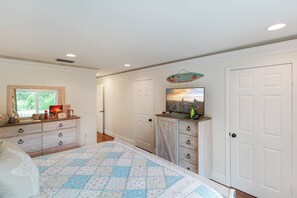 Une chambre à coucher avec un lit, une commode et un tableau représentant un paysage urbain accroché au mur.