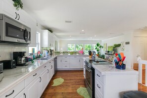 A modern kitchen with white cabinetry, stainless steel appliances, and a central island with a sink. - Private Siesta Key Pool Home Near Beaches - Siesta Sol (Sarasota)