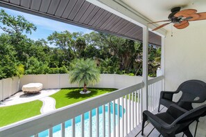 Un balcon avec piscine, un patio couvert et une vue sur un jardin luxuriant.