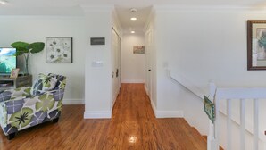 A hallway with wooden flooring, white walls, and a staircase leading to another level. - Private Siesta Key Pool Home Near Beaches - Siesta Sol (Sarasota)