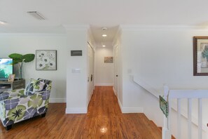 A hallway with wooden flooring, white walls, and a staircase leading to another level. - Private Siesta Key Pool Home Near Beaches - Siesta Sol (Sarasota)