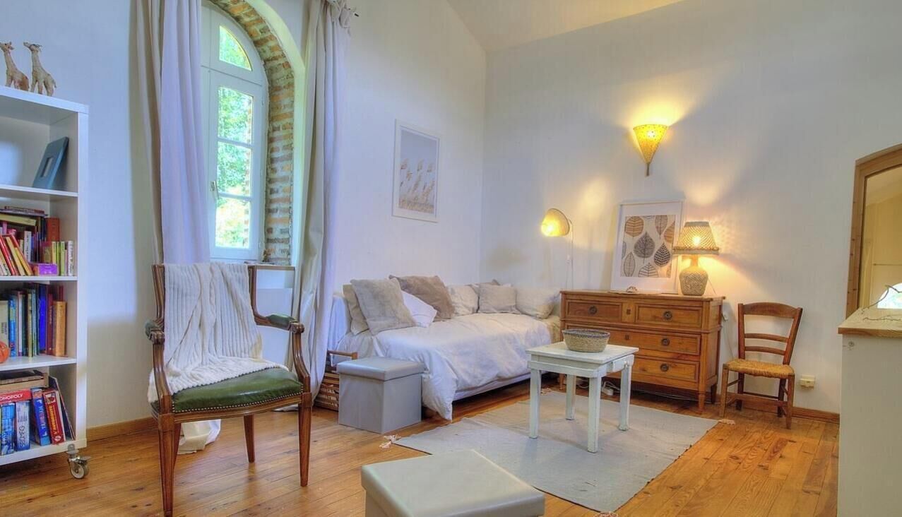 A bedroom with a bed, a chair, a dresser, a lamp, and a bookshelf.