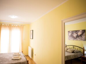 Ein Schlafzimmer mit einem Bett, einem Heizkörper, einem Gemälde und einem Fenster mit Vorhängen.
