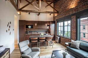 A modern kitchen with a central island, wooden cabinets, and a large window providing a view of the outside. - The Elevation Experience | All 6 Lofts ( up to 31 guests ) (Asheville)