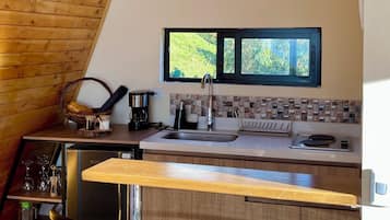 A kitchen with a wooden ceiling, a window, and two bar stools.