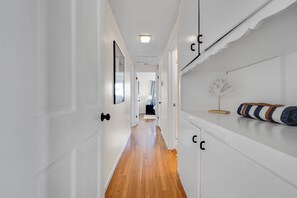 A hallway with white walls, wooden flooring, and a door with a black handle. - Welcoming 3-bedroom house in Malibu perfect for your getaway (Malibu)