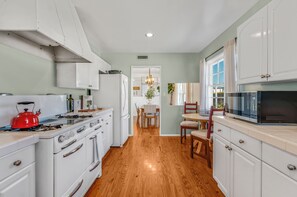 A kitchen with white cabinets, a red kettle, and a wooden floor. - Welcoming 3-bedroom house in Malibu perfect for your getaway (Malibu)