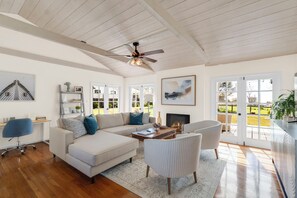 A spacious living room with a high ceiling, a fireplace, and large windows. - Welcoming 3-bedroom house in Malibu perfect for your getaway (Malibu)