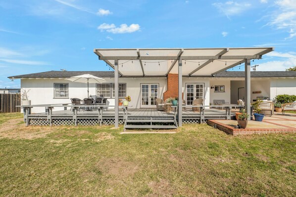A two-story house with a covered patio, a brick fireplace, and a fenced yard.