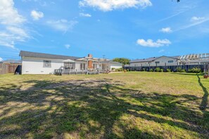 A residential property with a spacious backyard, a covered patio, and a two-story house.