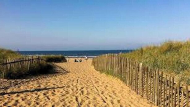A sandy beach path with a wooden fence on one side and a grassy dune on the other, leading to the sea. - Luxury Caravan situated on Holistic wellbeing site (Mablethorpe)