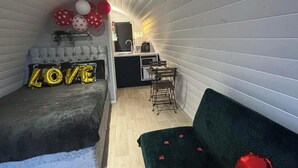 Et kompakt værelse med en seng, et lille tekøkken, en sofa og et barområde.