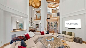 A spacious living room with a large sectional sofa, a coffee table, and a bookshelf. - Spacious 5BR Vail retreat with river views and fireplace (Vail)