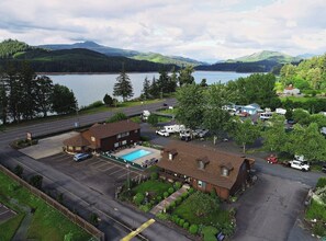 A hotel with a swimming pool, RV parking, and a view of a lake and mountains.