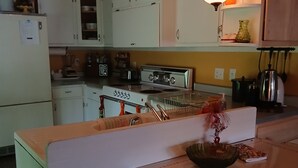 A kitchen with white cabinets, a stove, and a dining area with a table and chairs.
