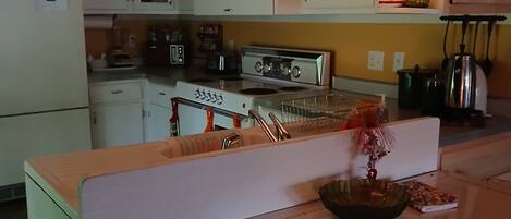 A kitchen with white cabinets, a stove, and a dining area with a table and chairs.