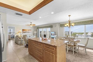 A spacious kitchen with a large island, dining area, and a view of the city. - Beachfront Dual Condo Escape with Pool, Gulf Views & Beach Access for Groups - Sand Caper - Roelens (Fort Myers Beach)