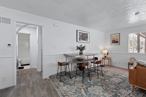A modern kitchen with a dining area, a bar stool setup, and a patterned rug. - 1BR Cozy SLC Retreat Near Downtown & Trails (Salt Lake City)