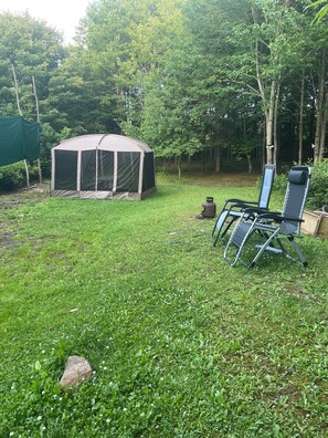 A tent set up in a grassy area with trees in the background, a gas canister, and two camping chairs. - Glamping get-a-way (Summit)