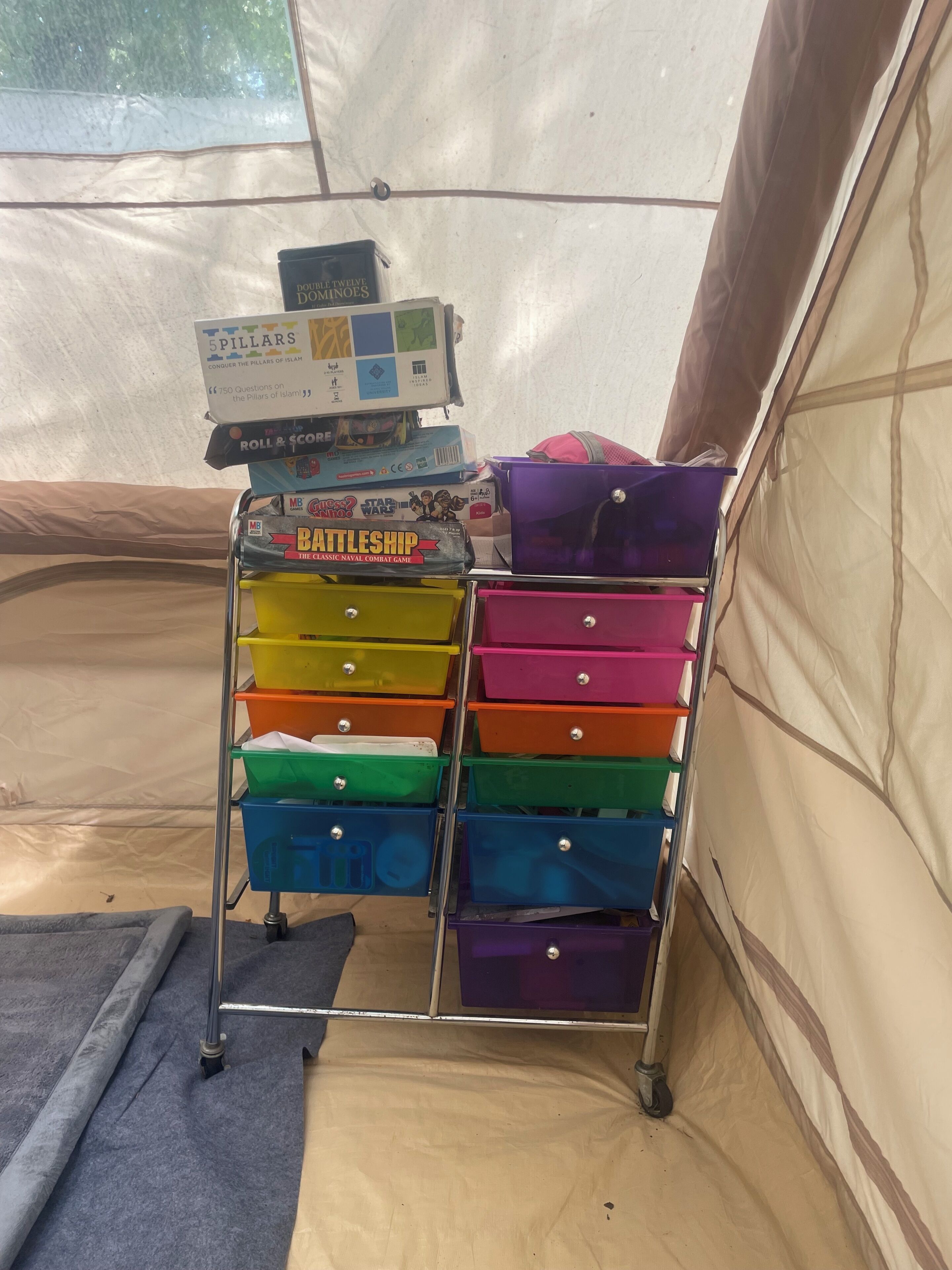 Een opslagkar met kleurrijke lades en een stapel spelletjes.