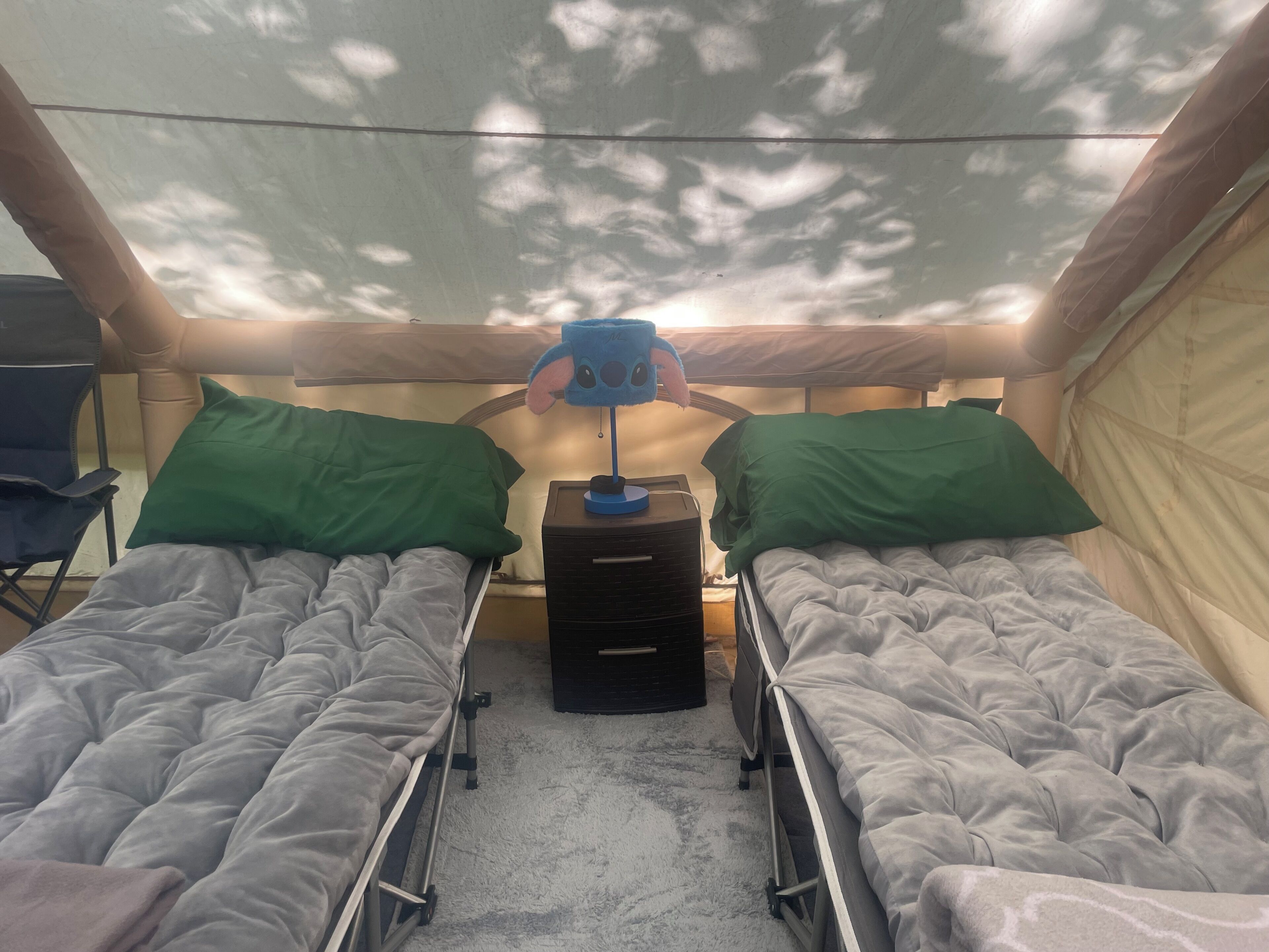 A tent with two beds, a desk, and a chair.