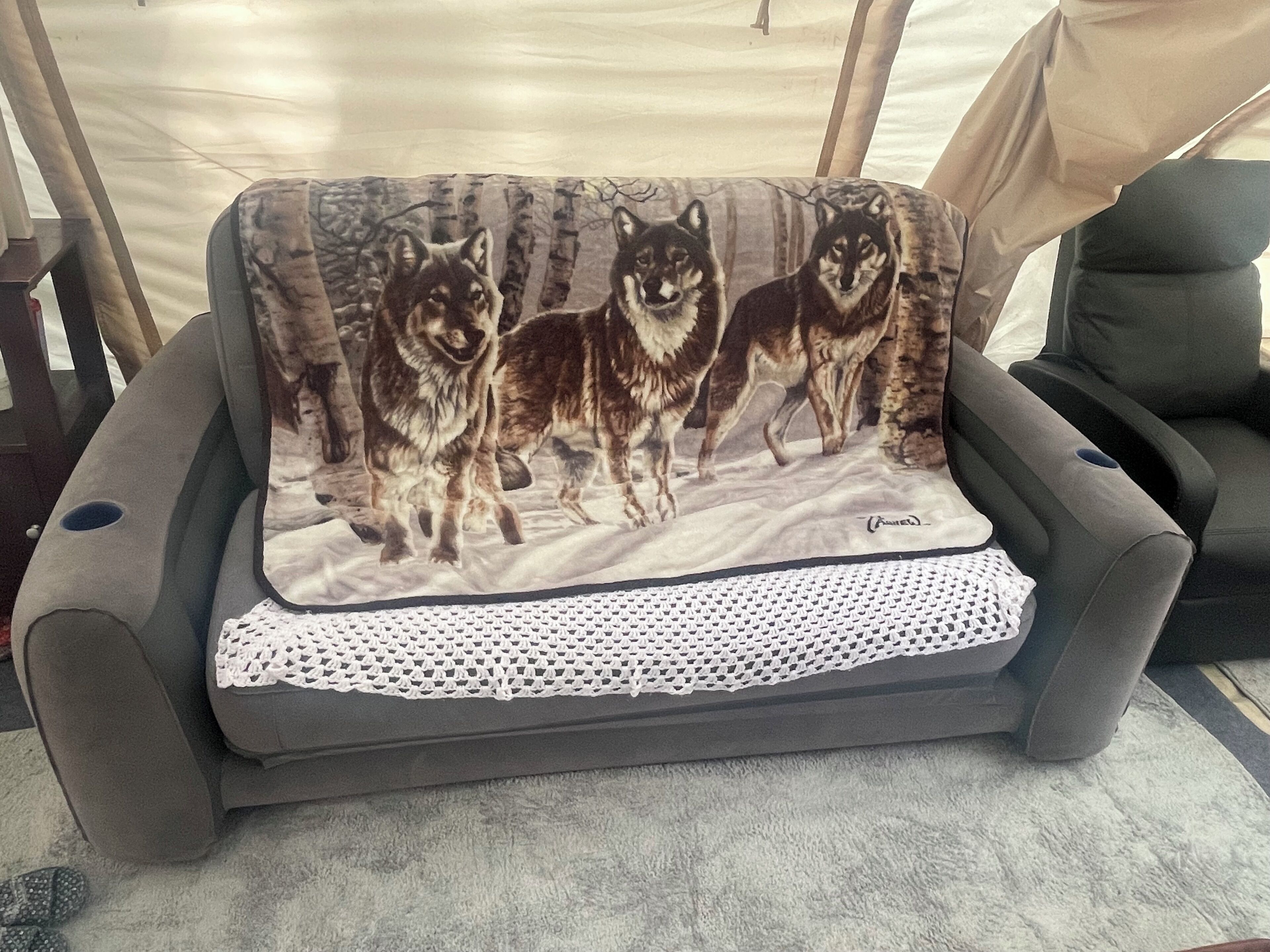 Un canapé agrémenté d’un coussin à motifs représentant des illustrations de loups.