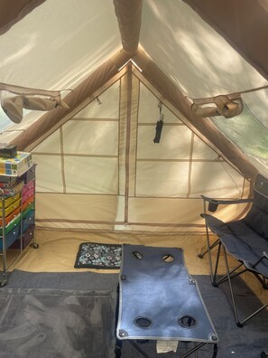 A tent interior with a sleeping area, a storage unit, and a table.