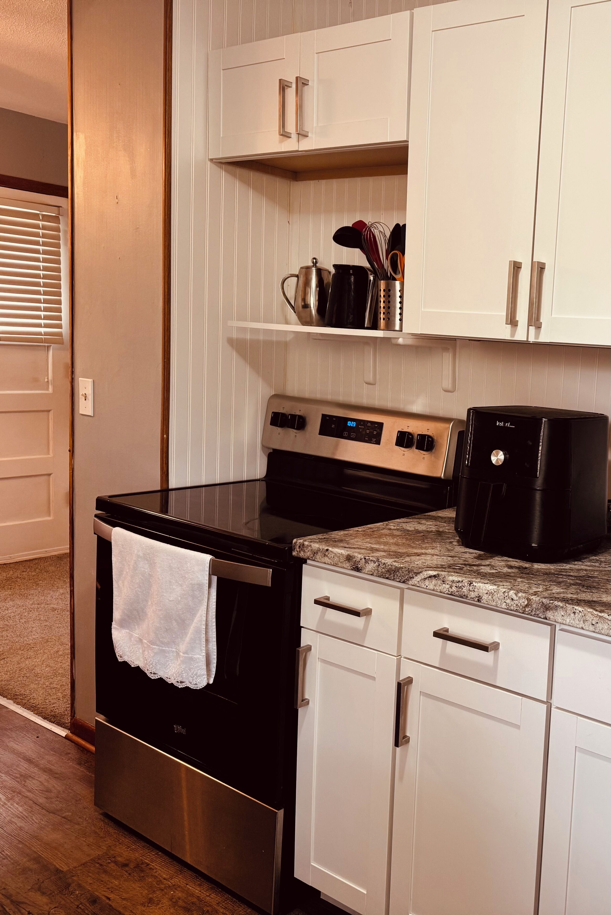 A kitchen with a stainless steel stove, white cabinets, and a countertop with a coffee maker.